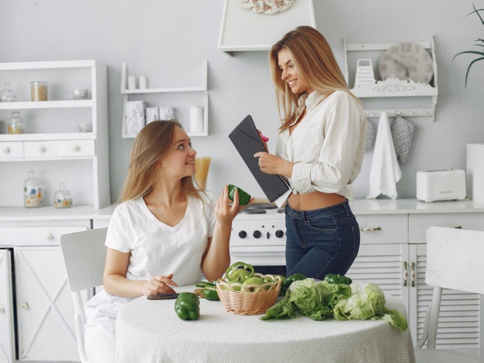 Beautiful and sporty girls in a kitchen with a vegetables