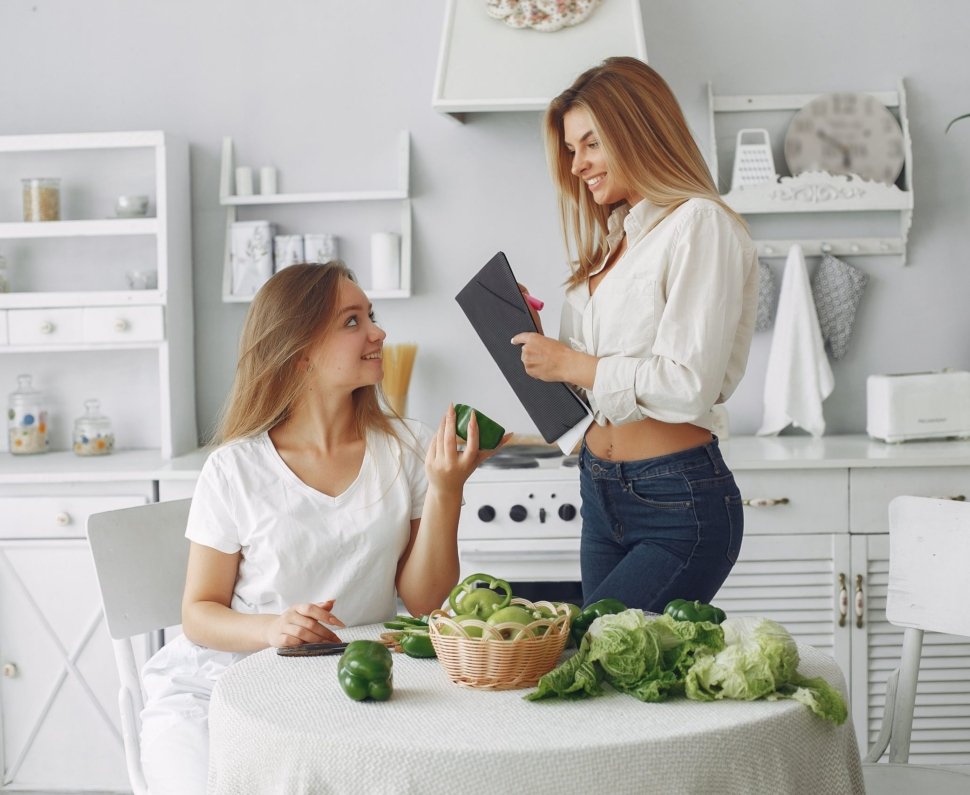 Beautiful and sporty girls in a kitchen with a vegetables
