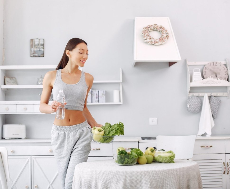 Beautiful and sporty girl in a kitchen with a vegetables